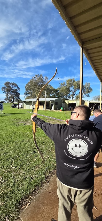 A Happiness Crew participant trying archery outdoors