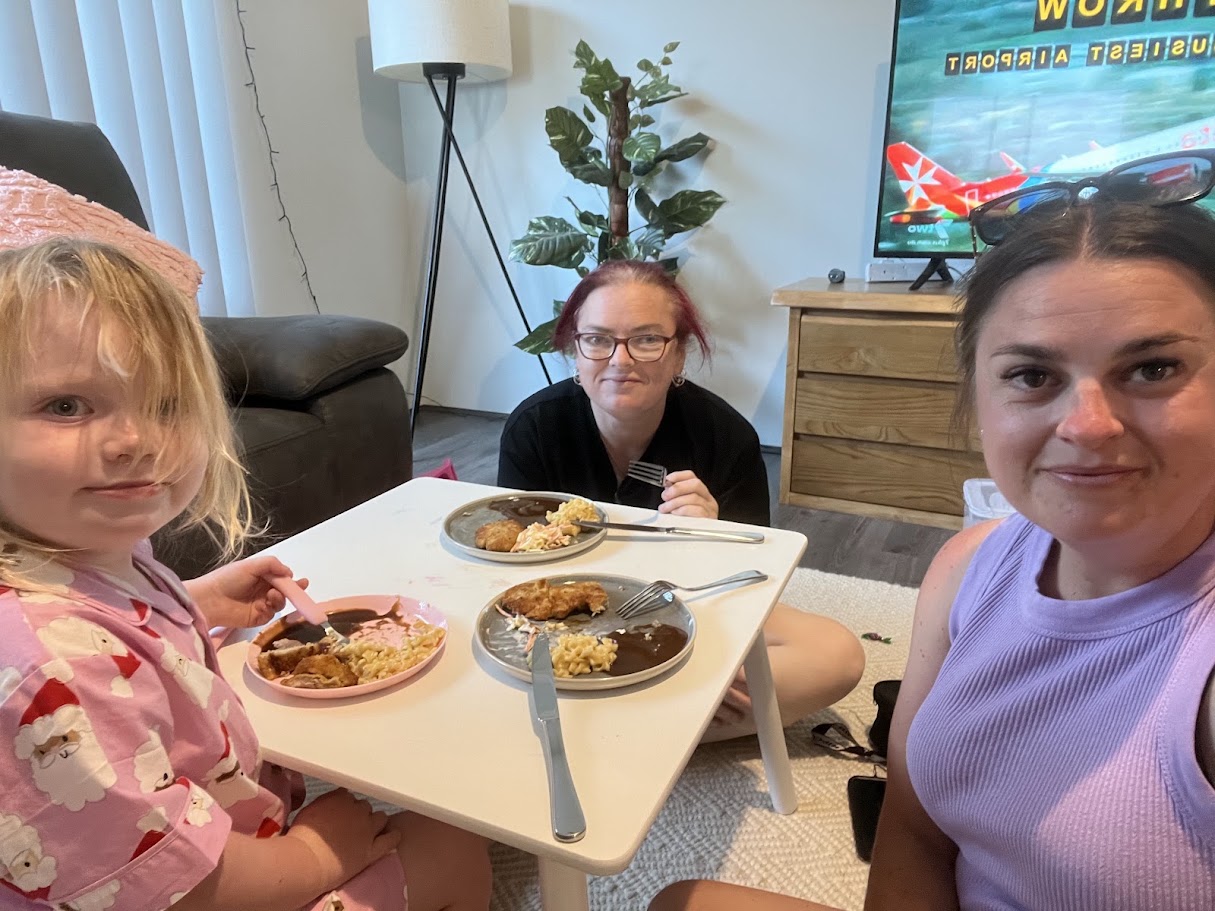 A mum receiving Happiness Crew support at home while sharing a meal with her child.