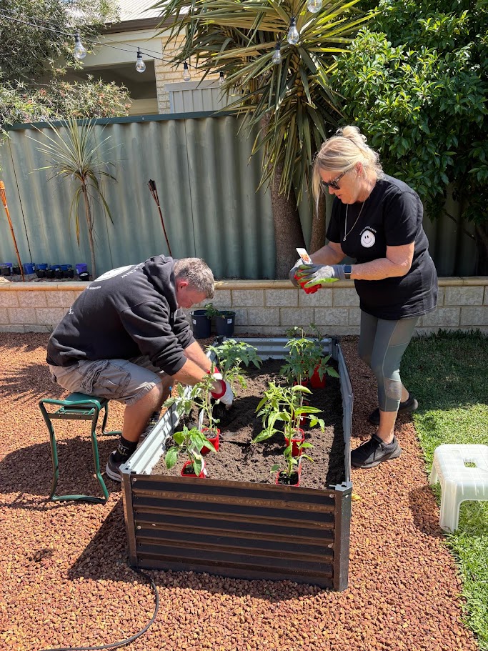 A participant and Crew member working together in a home garden