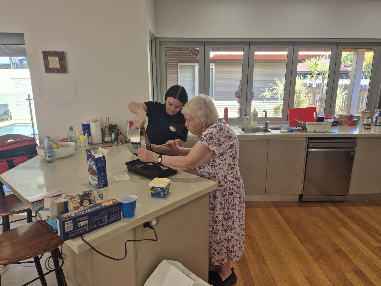 A participant and Crew member baking together in a home kitchen